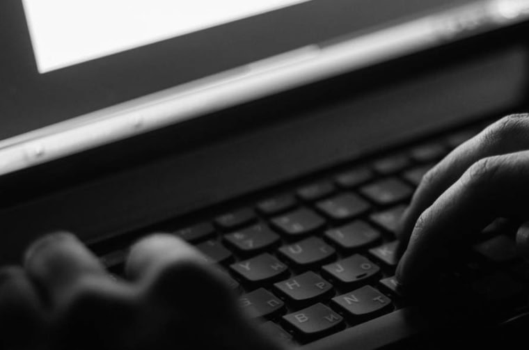 photo of someone looking suspicious at a laptop to illustrate hacking