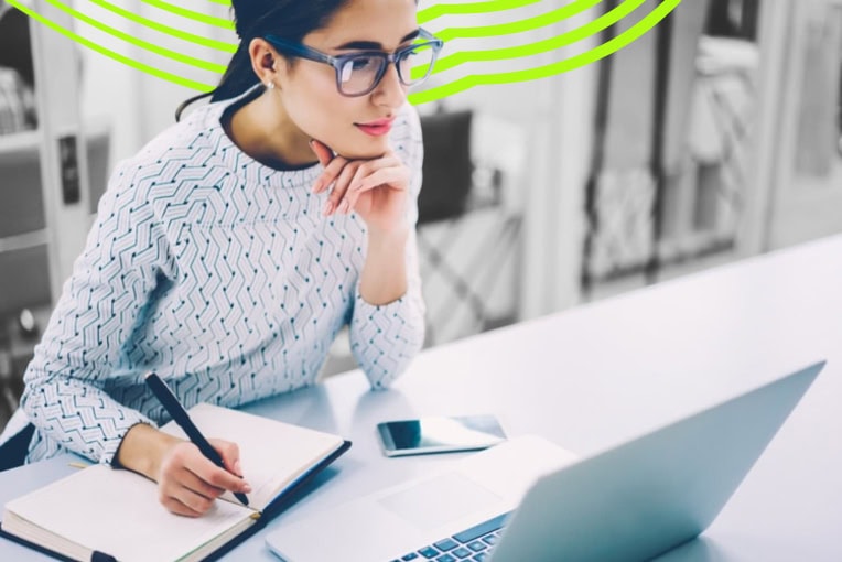 woman writing at computer with notebook