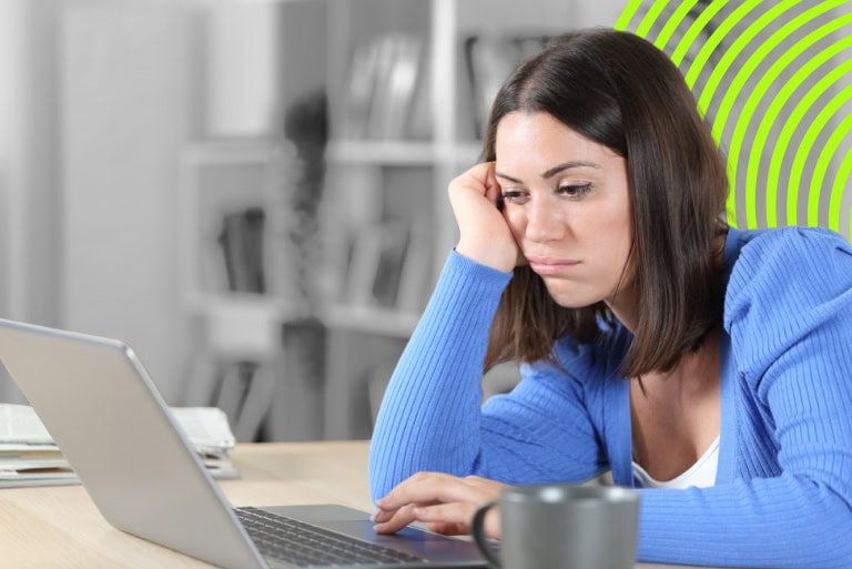 woman sat at a computer looking bored waiting for a slow website to load