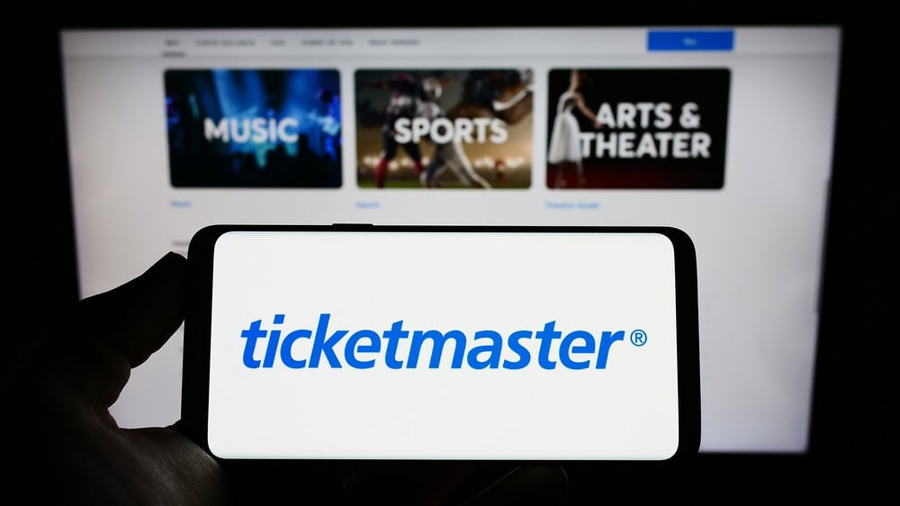 Ticketmaster logo on an smartphone screen, with their website on a laptop in the background