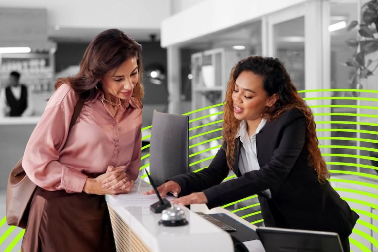 A hotel check in desk with a woman standing behind it.