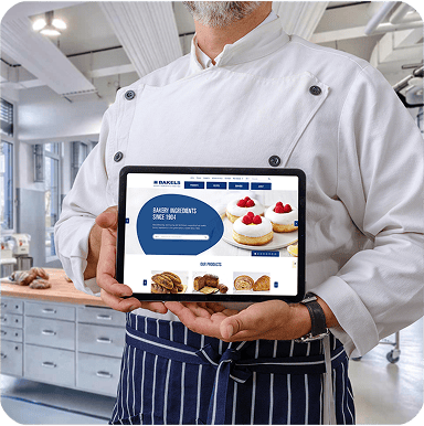 The Bakels website on a tablet, being held by a baker in a Bakels kitchen